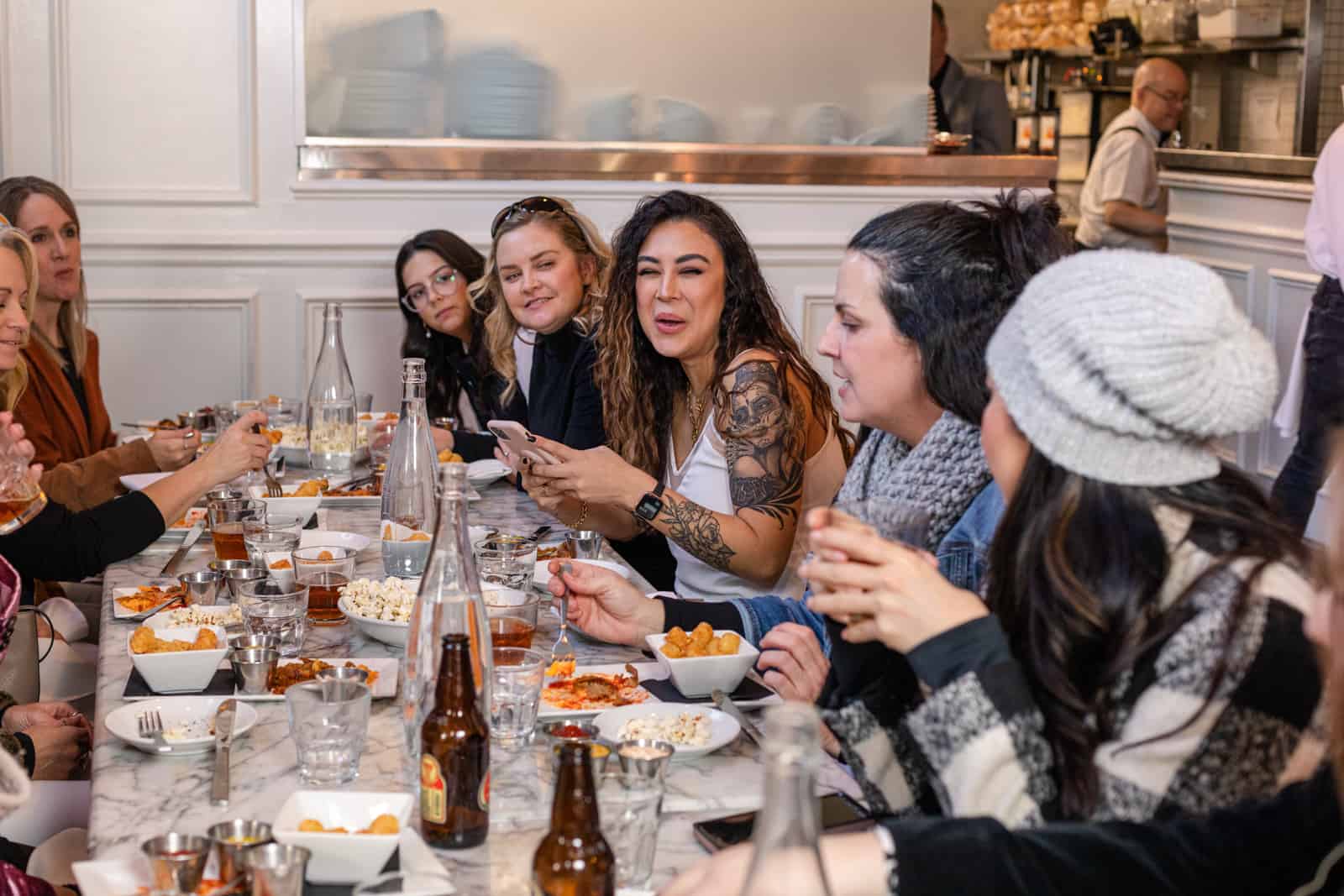 View of long table with women eating at restaurant.